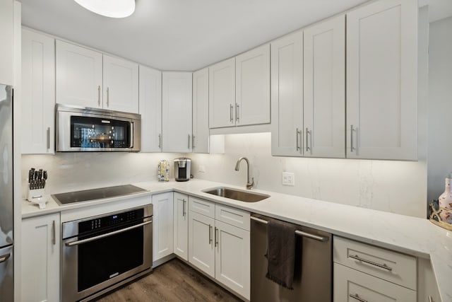 kitchen featuring white cabinets, dark hardwood / wood-style floors, stainless steel appliances, light stone countertops, and sink