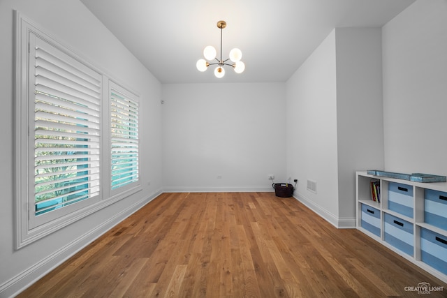 unfurnished room featuring a chandelier and light hardwood / wood-style floors