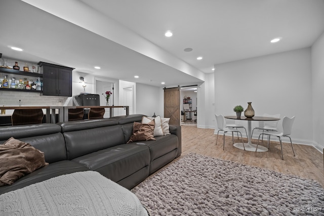 living room with a barn door and light hardwood / wood-style flooring