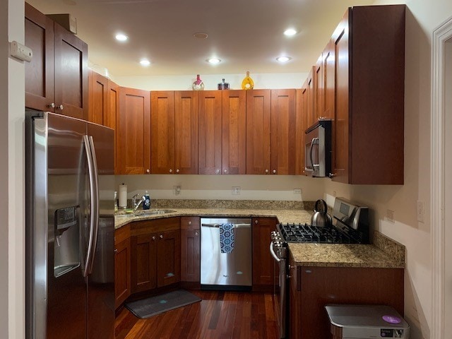 kitchen with light stone countertops, sink, stainless steel appliances, and dark hardwood / wood-style floors