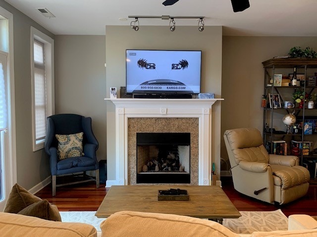 living room featuring track lighting, ceiling fan, and dark hardwood / wood-style flooring