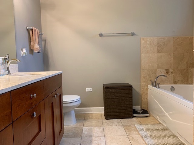 bathroom with vanity, tile flooring, a washtub, and toilet