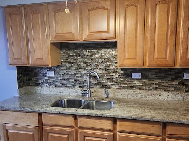 kitchen featuring backsplash, light stone counters, and sink