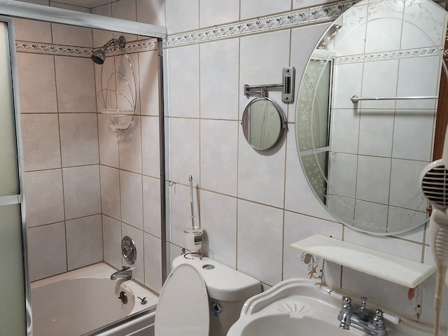 full bathroom featuring enclosed tub / shower combo, tile walls, toilet, and sink