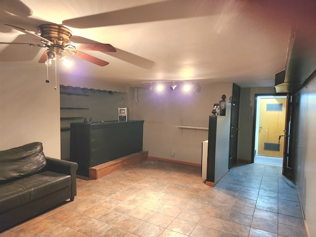 basement with light tile floors, rail lighting, and ceiling fan