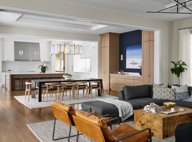 living room featuring dark wood-type flooring, a chandelier, and a raised ceiling