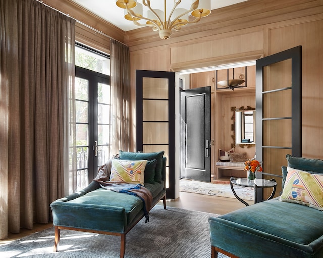 sitting room with french doors, an inviting chandelier, dark hardwood / wood-style flooring, and wood walls