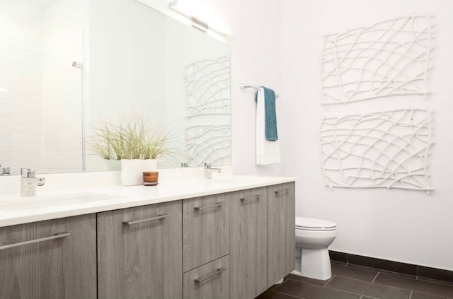 bathroom featuring double vanity, baseboards, toilet, tile patterned flooring, and a sink