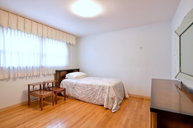 bedroom featuring light wood finished floors and baseboards