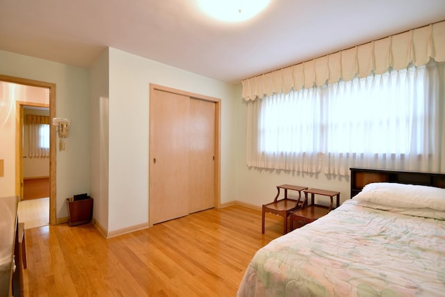 bedroom with wood finished floors, a closet, and baseboards