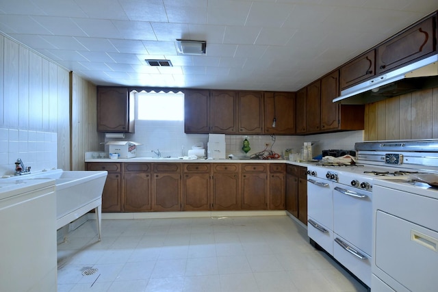 kitchen with double oven range, light countertops, under cabinet range hood, and light floors