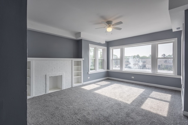 spare room with built in features, ceiling fan, carpet floors, and a fireplace