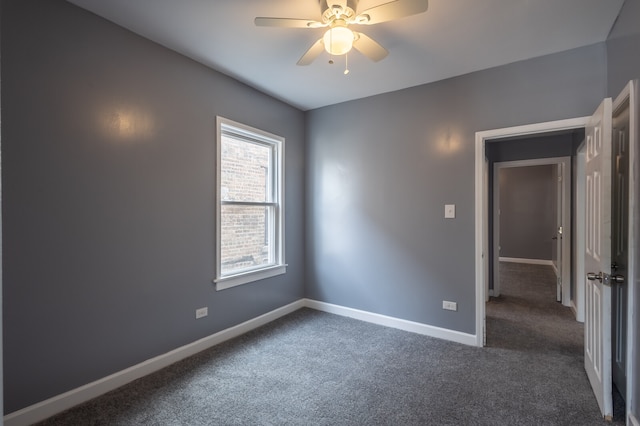 empty room featuring ceiling fan and dark colored carpet