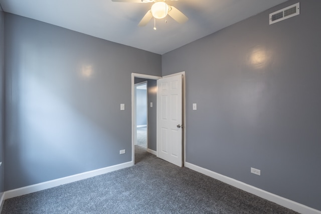 empty room with ceiling fan and dark carpet