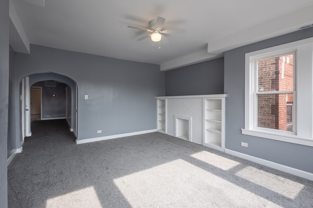 unfurnished living room with ceiling fan and dark colored carpet