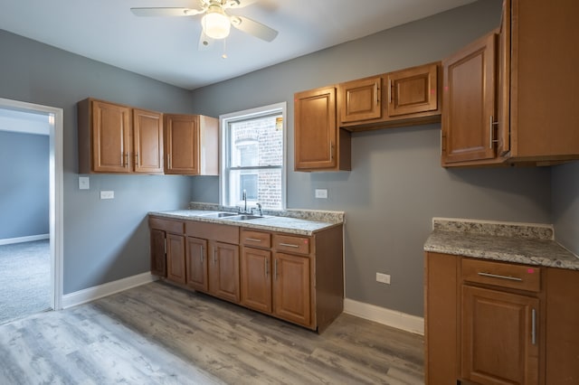 kitchen with ceiling fan, sink, and light wood-type flooring