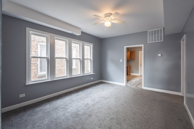 unfurnished bedroom with ceiling fan, dark carpet, and multiple windows