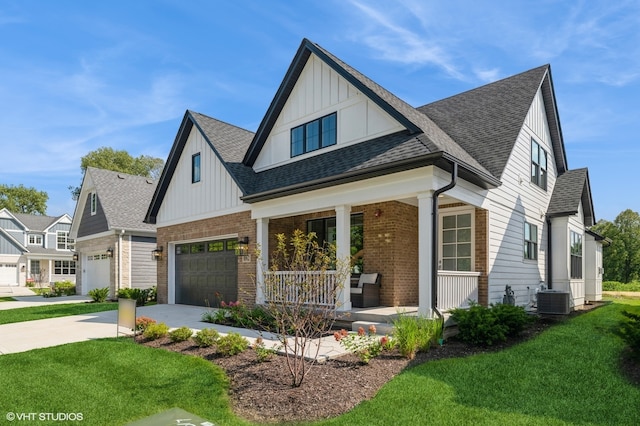 view of front of house with a garage, central AC unit, a front lawn, and covered porch