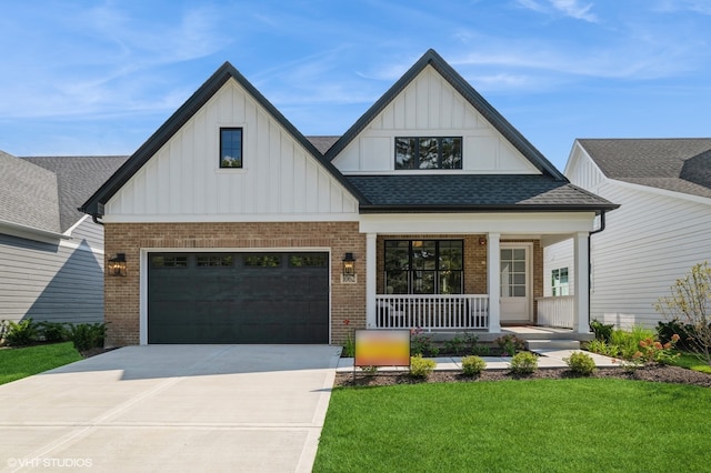 view of front of house featuring covered porch, a garage, and a front lawn