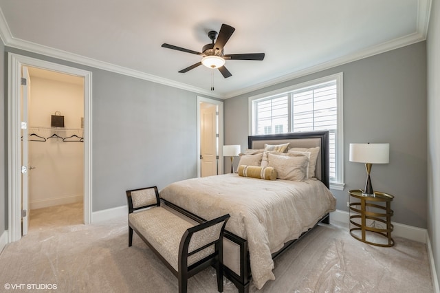 bedroom with a walk in closet, crown molding, ceiling fan, and light colored carpet