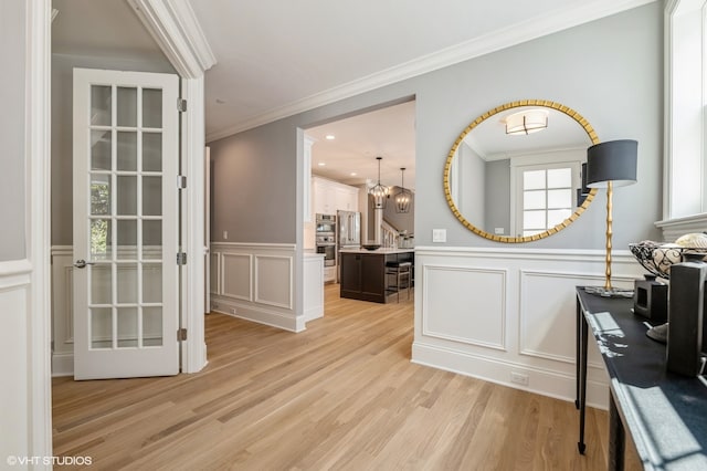 interior space featuring light wood-type flooring, crown molding, and an inviting chandelier