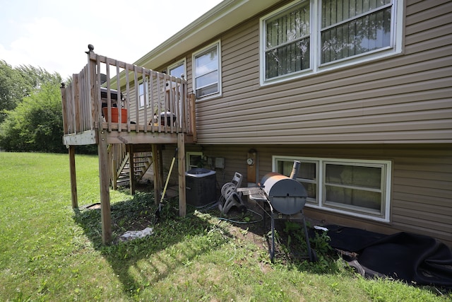 back of property with a deck, central AC, and a lawn