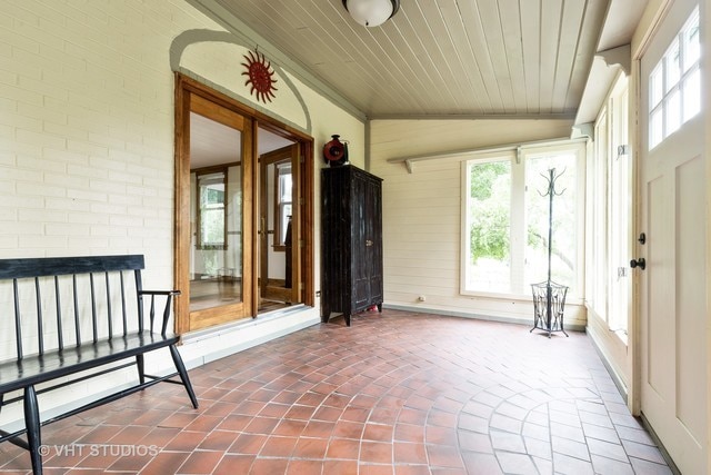 unfurnished sunroom featuring a fireplace, wood ceiling, and vaulted ceiling