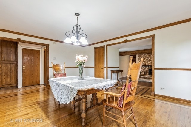 dining room featuring crown molding, a notable chandelier, and light wood-type flooring