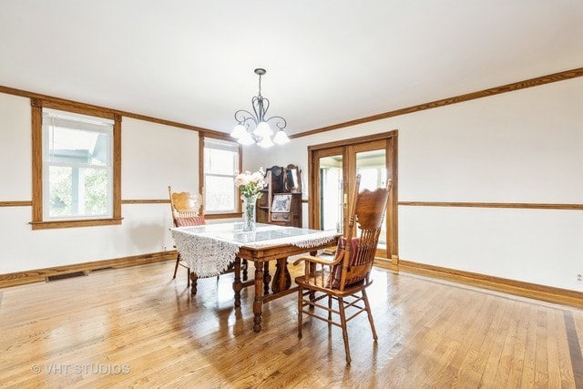 dining space featuring a notable chandelier, ornamental molding, and light hardwood / wood-style floors