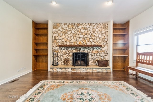 unfurnished living room featuring built in shelves, dark wood-type flooring, and a fireplace