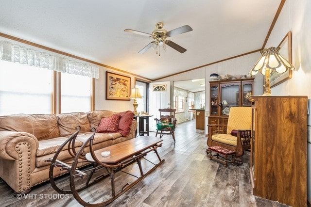 living room with lofted ceiling, crown molding, ceiling fan, and dark hardwood / wood-style flooring