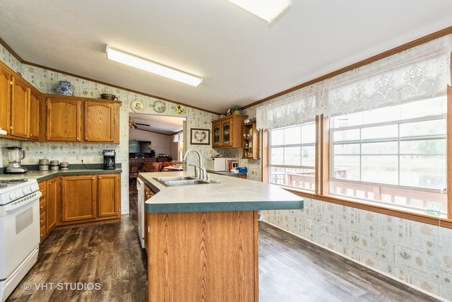 kitchen with white gas range oven, crown molding, lofted ceiling, a kitchen island with sink, and sink