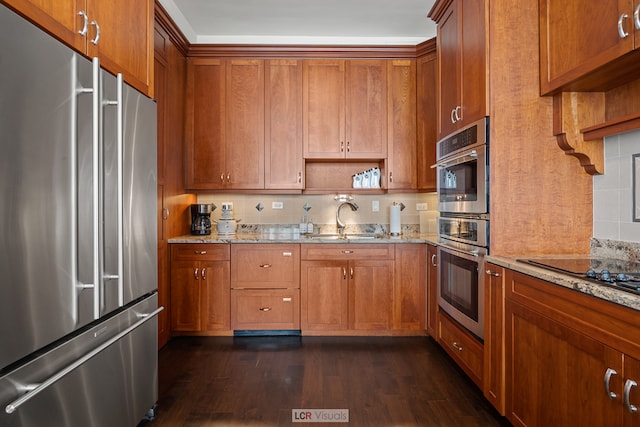 kitchen with dark hardwood / wood-style flooring, sink, stainless steel appliances, and light stone countertops