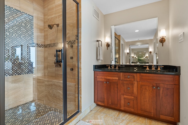 bathroom with tile floors, vanity with extensive cabinet space, double sink, and a shower with shower door