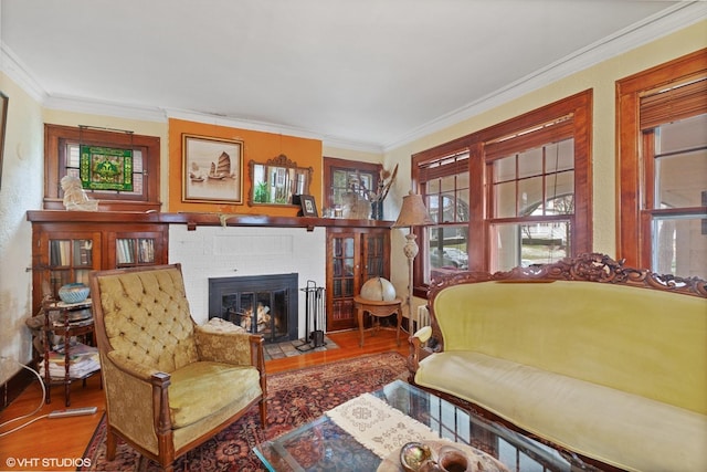 sitting room with wood-type flooring, a brick fireplace, and ornamental molding