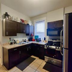 kitchen featuring light tile floors, stainless steel fridge, dark brown cabinetry, and gas range