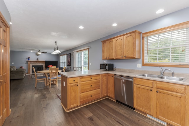 kitchen featuring dark wood-type flooring, stainless steel dishwasher, kitchen peninsula, pendant lighting, and sink