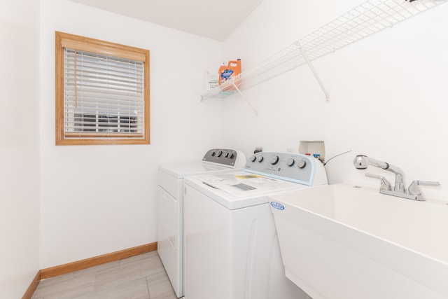 clothes washing area featuring light tile floors, separate washer and dryer, and sink