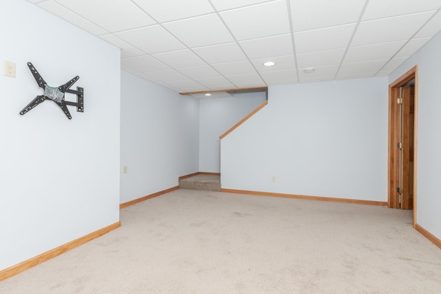 basement featuring a paneled ceiling and light colored carpet