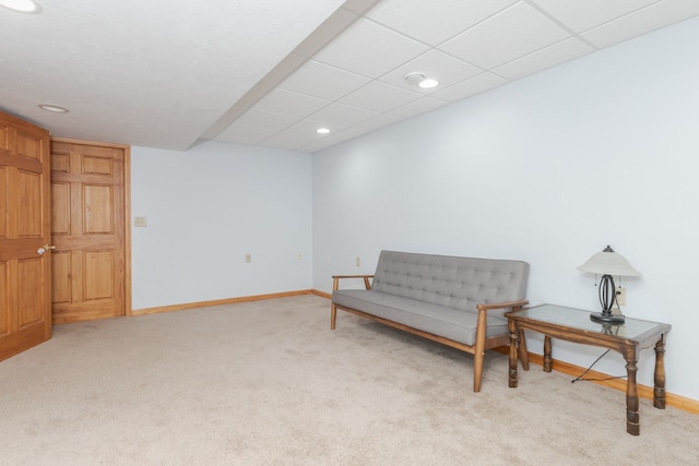 living area with light colored carpet and a paneled ceiling