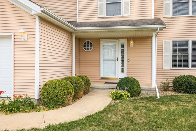 view of exterior entry with a lawn and a garage