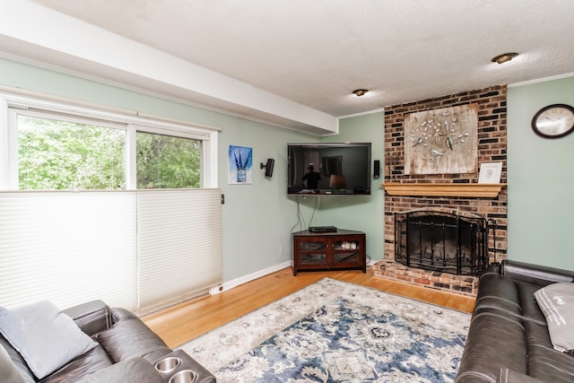 living room with wood-type flooring, a textured ceiling, a fireplace, and ornamental molding