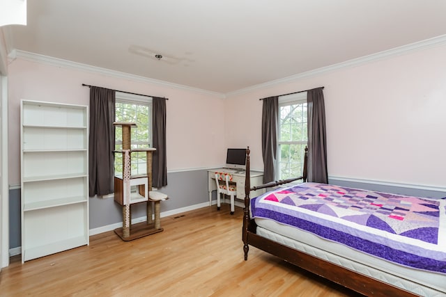 bedroom with multiple windows, crown molding, and hardwood / wood-style flooring