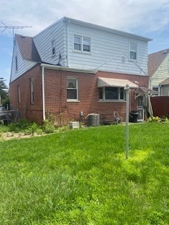 back of property featuring central air condition unit and a lawn