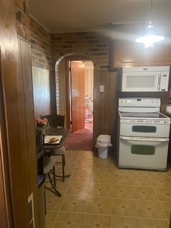 kitchen featuring white appliances, brick wall, and light tile flooring