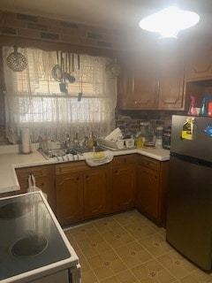 kitchen featuring backsplash, stainless steel refrigerator, and decorative light fixtures