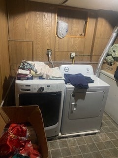 washroom with wooden walls, tile floors, and washer and dryer