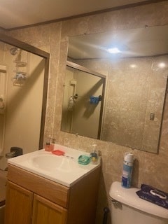 bathroom with tile walls, toilet, an enclosed shower, and vanity with extensive cabinet space