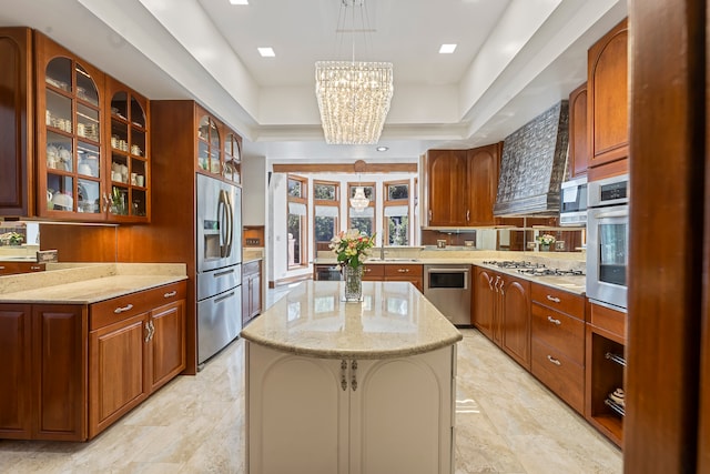 kitchen featuring light stone countertops, a center island, an inviting chandelier, pendant lighting, and appliances with stainless steel finishes