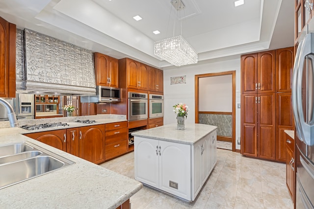 kitchen featuring stainless steel appliances, sink, pendant lighting, white cabinetry, and a kitchen island